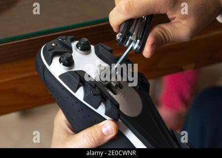 Primo piano delle mani di un uomo che monta le scarpe da strada in carbonio da ciclismo e le scarpe da corsa per i pedali. Concetto sportivo, preparazione per il ciclismo. Foto Stock