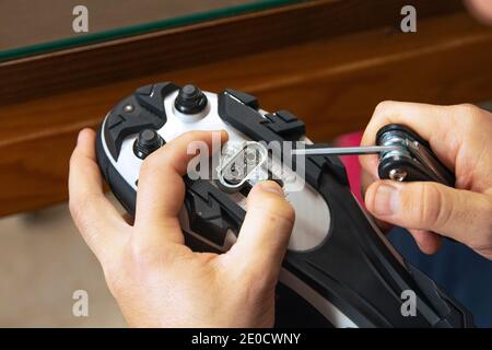 Primo piano delle mani di un uomo che monta le scarpe da strada in carbonio da ciclismo e le scarpe da corsa per i pedali. Concetto sportivo, preparazione per il ciclismo. Foto Stock