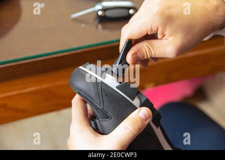 Primo piano delle mani di un uomo che monta le scarpe da strada in carbonio da ciclismo e le scarpe da corsa per i pedali. Concetto sportivo, preparazione per il ciclismo. Foto Stock