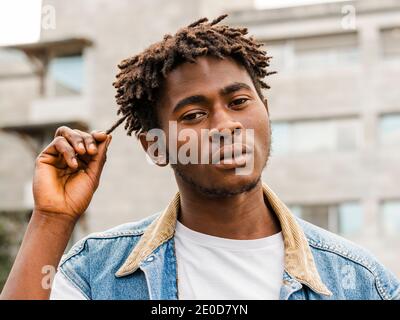 Fiducioso nero e bianco del serio giovane hipster afroamericano Maschio con acconciatura Afro guardando la macchina fotografica Foto Stock