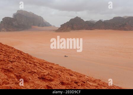 Vista panoramica dell'auto a cavallo nella valle di arenaria a Wadi Rum nel giorno nuvoloso Foto Stock