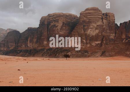 Scenario cupo di rocce ruvide nella valle di arenaria di Wadi Rum il giorno nuvoloso Foto Stock