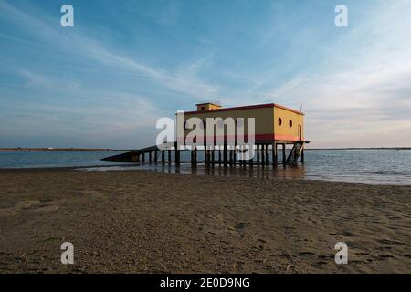 Casa bagnino situata sulla spiaggia di sabbia bagnata Fuseta sullo sfondo Di mare e cielo di tramonto in Algarve Foto Stock