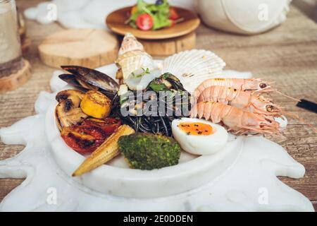 Piatto con vari tipi di frutti di mare e verdure alla griglia con Uova sode servite a tavola durante il pranzo in hotel taiwanese Foto Stock