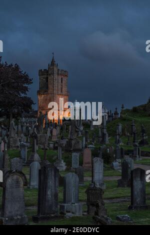Scenario di cimitero invecchiato con vecchie lapidi situato vicino al castello In serata buia in Scozia Foto Stock