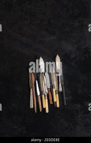 Dall'alto della collezione di coltelli d'annata messi in nero sfondo in studio Foto Stock