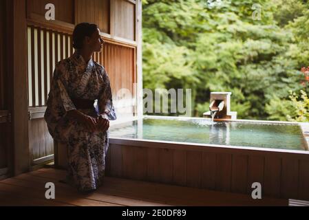 Giovane donna caucasica in un kimono che si prepara a godere. Un rilassante e tradizionale bagno termale acque termali ad un giapponese onsen, vista laterale Foto Stock