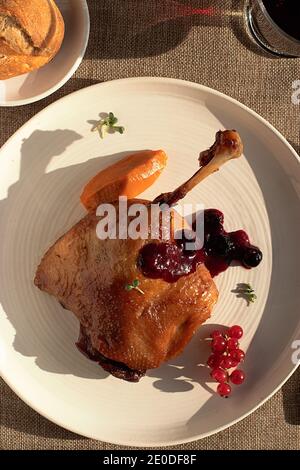 Dall'alto delizioso confit di anatra fritta su piastra di ceramica bianca posto sul tavolo di un ristorante moderno Foto Stock