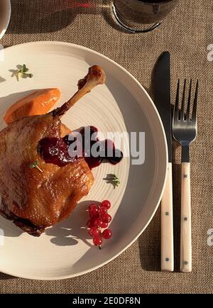 Dall'alto delizioso confit di anatra fritta su piastra di ceramica bianca posto sul tavolo di un ristorante moderno Foto Stock