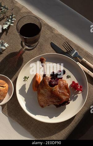 Dall'alto delizioso confit di anatra fritta su piastra di ceramica bianca posto sul tavolo di un ristorante moderno Foto Stock