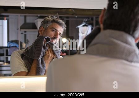 Dopo aver rasato la barba, fate scattare una foto dell'uomo di mezza età con i capelli grigi utilizzando un asciugamano. Foto Stock