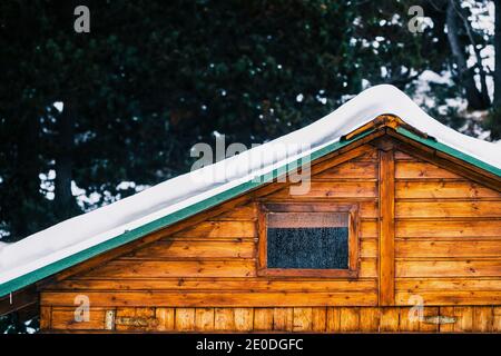 Accogliente tipica casa in legno con tetto innevato e piccola finestra coperto di brina il giorno d'inverno Foto Stock