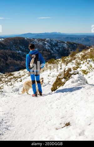 Uomo adulto meccanico in occhiali protettivi e respiratore con blu hardhat guardando la macchina fotografica mentre si è in piedi vicino all'edificio dell'officina via Foto Stock