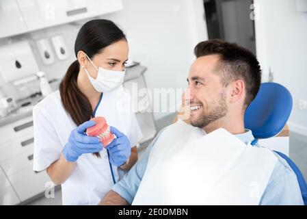 Dentista femmina mantenendo i campioni a ganascia dente con bretelle modello. Professional dental clinic. Foto Stock