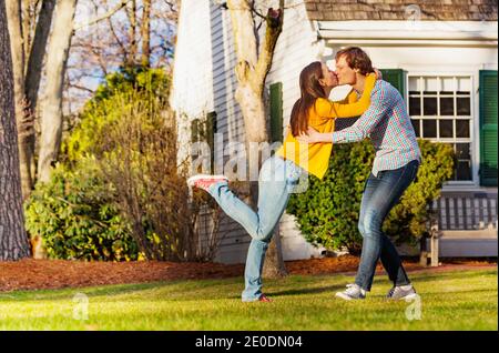 Coppia danzante fuori nel parco in piedi su una gamba baciarsi e avere una vista divertente da un lato Foto Stock