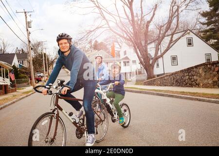 Famiglia con Ritratto di un bambino giro su un la moto tandem di traino è collegata al padre sulla strada urbana Foto Stock