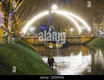 Duesseldorf, Germania. 31 dicembre 2020. I servizi di emergenza tirano una macchina fuori dalla fossa Kö di Königsallee, che in precedenza era entrata in acqua. Secondo un giornalista del dpa, la macchina si era precedentemente schiantata attraverso la recinzione e sbarcata nel fosso che divide Königsallee in due lati. Il conducente salì sul tetto della vettura e fu salvato da lì. Credit: David Young/dpa/Alamy Live News Foto Stock