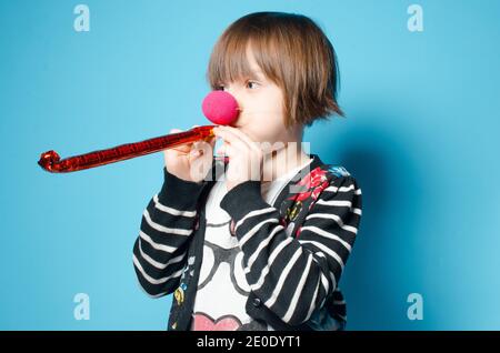 La bambina bruna con un falso naso celebra un compleanno. Il concetto di compleanno. Foto Stock