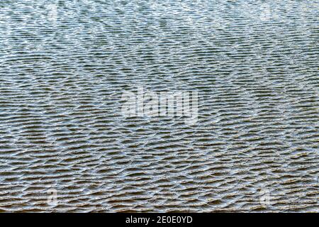 Piccole increspature su un lago. Il vento causa increspature più piccole sulle increspature principali. Foto Stock