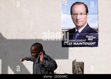 Un bambino di un quarto di Les Ulis corre sotto il manifesto della campagna elettorale del candidato francese del Partito socialista di opposizione (PS) alle elezioni presidenziali francesi del 2012, Francois Hollande, durante una visita di campagna a Les Ulis, fuori Parigi, Francia, il 7 aprile 2012. Foto di Stephane Lemouton/ABACAPRESS.COM. Foto Stock