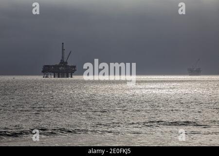 Oil Derrick e surfisti al largo della costa di Huntington Beach, Orange County, California, Stati Uniti Foto Stock