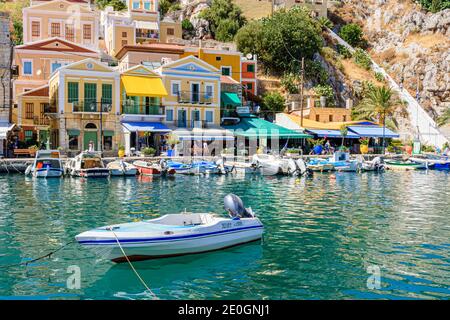 Colorate case neoclassiche e barche nel porto di Gialos, isola di Symi, Grecia Foto Stock