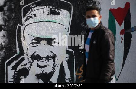 Gaza, Palestina. 31 dicembre 2020. Un uomo passa accanto a un murale di graffiti raffigurante il leader politico palestinese e fondatore del movimento Fatah, segno di commemorazione del 56° anniversario della fondazione del partito politico a Gaza, il 31 dicembre 2020. (Foto di Mahmuod Khattab/INA Photo Agency/Sipa USA) Credit: Sipa USA/Alamy Live News Foto Stock