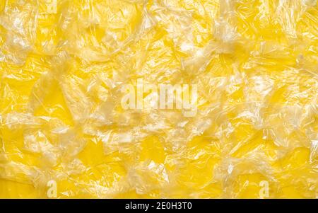 Vista dall'alto con una moltitudine di sacchetti monouso su sfondo giallo. Fondo full-frame con molti sacchetti di plastica. Foto Stock