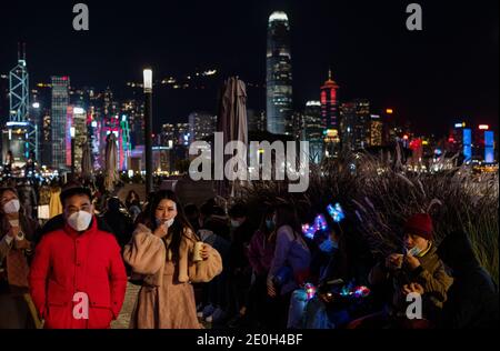 La gente celebra la vigilia di Capodanno indossando maschere protettive sul lungomare del porto di Victoria, nonostante il governo di Hong Kong abbia annullato le celebrazioni dei fuochi d'artificio e limitato le riunioni pubbliche a Hong Kong, in Cina, il 31 dicembre 2020. Hong Kong entra nell'anno 2021 con le più severe regole di distanza sociale COVID-19 e la quarantena estesa per i viaggiatori che arrivano a Hong Kong fino a 21 giorni. Foto Stock