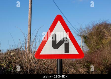 Segnale stradale a triangolo rosso per segnalare curve strette che precedono, Regno Unito Foto Stock