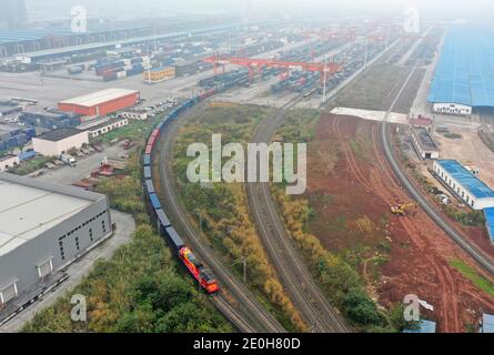 (210101) -- CHONGQING, 1 gennaio 2021 (Xinhua) -- Foto aerea mostra un treno merci Cina-Europa diretto a Duisburg della Germania con partenza dalla stazione di Tuanjiecun a Chongqing, 1 gennaio 2021. A più di 300 km di distanza a Chengdu, provincia di Sichuan, un altro treno merci Cina-Europa diretto per la Polonia parte lo stesso giorno. Lanciati a Chongqing e Chengdu rispettivamente nel 2011 e nel 2013, i servizi di trasporto ferroviario merci Cina-Europa hanno ridotto significativamente la distanza tra la Cina occidentale e l'Europa. Finora, circa 14,000 treni merci hanno collegato le due città con l'Europa, uno Foto Stock