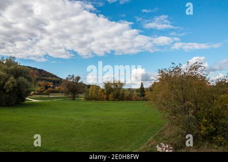 Foglie colorate, prati verdi e il cielo blu nuvoloso Foto Stock