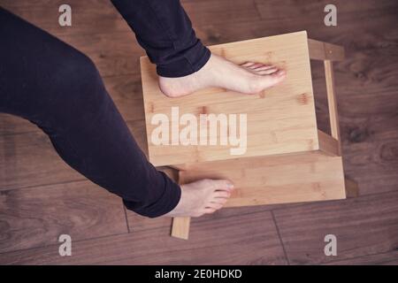 Una donna adulta cade da una scala a causa di una gamba sedia rotta. Problemi con la protezione del lavoro quando si lavora a casa Foto Stock