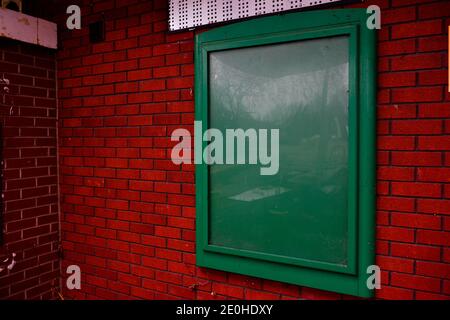 Cornice pubblicitaria quadrata verde fissata alla parete esterna in mattoni Foto Stock