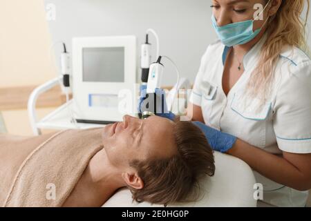 Inquadratura tagliata di un estetista in maschera medica di lavoro durante la pandemia del coronavirus Foto Stock