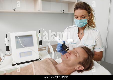 Cosmetologo professionista che lavora durante la pandemia, indossando maschera medica viso presso la sua clinica di bellezza Foto Stock