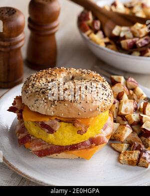 Sandwich con uova, pancetta e formaggio su un sacchetto con patate fritte Foto Stock