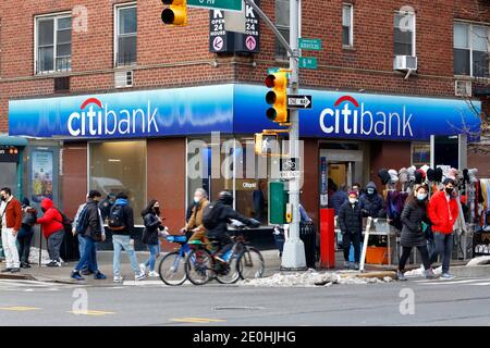 Persone che indossano maschere, ciclisti, pedoni, neve, venditori di strada, e Citibank all'angolo tra 6th Ave e W 23rd St a New York, New York. Dicembre 2020 Foto Stock