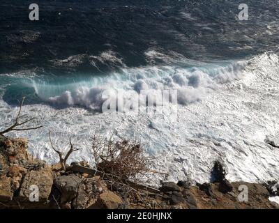 Il mare azzurro infuocato con le onde che si infrangono contro la costa di Monemvasia, in Grecia, durante una giornata di tempesta Foto Stock