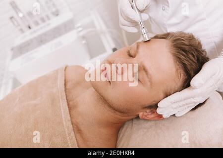 Bell'uomo rilassato ottenere trattamento di serraggio della pelle al salone di bellezza Foto Stock