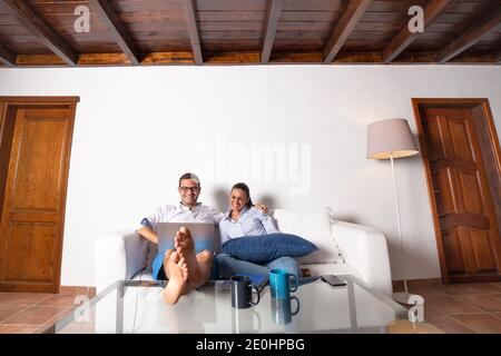 Giovane coppia adulta che si diverte a guardare un film sul proprio computer portatile nel salotto di casa. Foto Stock
