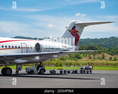 Scarico di bagagli e merci da un Fokker 100 chiamato Città del Laé da Air Niugini all'aeroporto di Wewak, chiamato anche aeroporto di Boram, a Wewak, la capitale Foto Stock