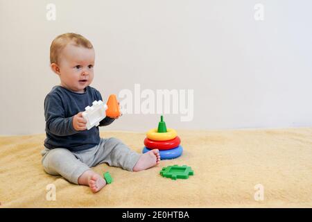 Bambino che puzzava e gioca con giocattoli colorati a casa. Sfondo bambino con spazio per la copia. Sviluppo precoce per i bambini. Foto Stock