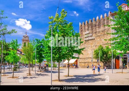 Guimaraes, Portogallo, 24 giugno 2017: Torre de Alfandega vecchia torre medievale Aqui Nasceu Portogallo e Jardins da Alameda giardini parco con alberi verdi nel centro storico della città di Guimaraes Foto Stock