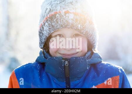 Ritratto invernale di un ragazzo sorridente nella neve Foto Stock