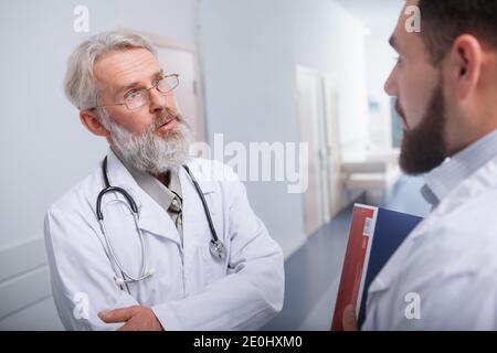 Anziano medico di sesso maschile guardando preoccupato, parlando con il suo collega presso la clinica Foto Stock