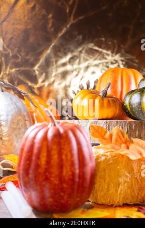 Piccola zucca rossa accanto al fieno coperto di foglie, zucche d'arancia, zucca d'arancia, e una zucca verde su legno accanto ad una zucca d'argento con una b dorata Foto Stock