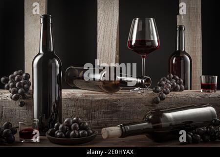 Bottiglie e bicchieri di vino rosso spagnolo e uva su base di legno su fondo nero. Foto Stock