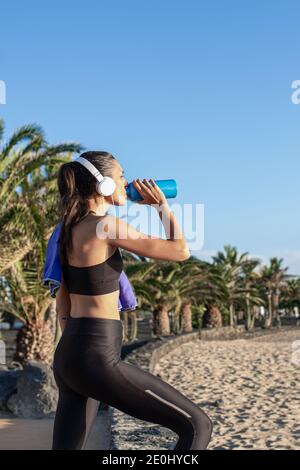 Bella donna fitness che beve acqua dopo l'allenamento in spiaggia . Foto Stock