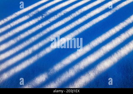 La recinzione in vinile bianco getta lunghe ombre invernali sulla neve fresca; Salida; Colorado; USA Foto Stock